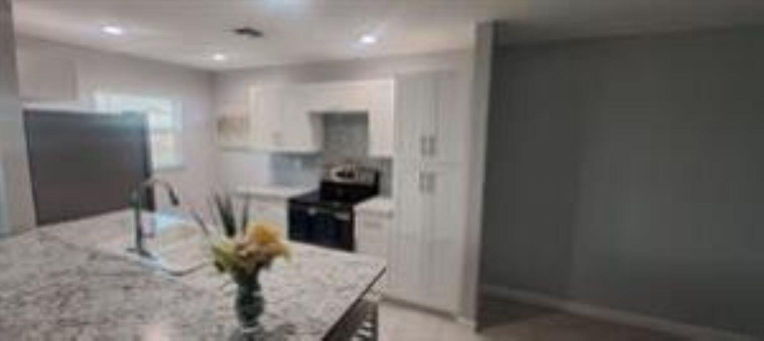 A kitchen features white cabinets, granite countertops, a center island, and stainless steel appliances — 14588 Canalview Drive # C, Delray Beach FL 33484, DELRAY BEACH, FL