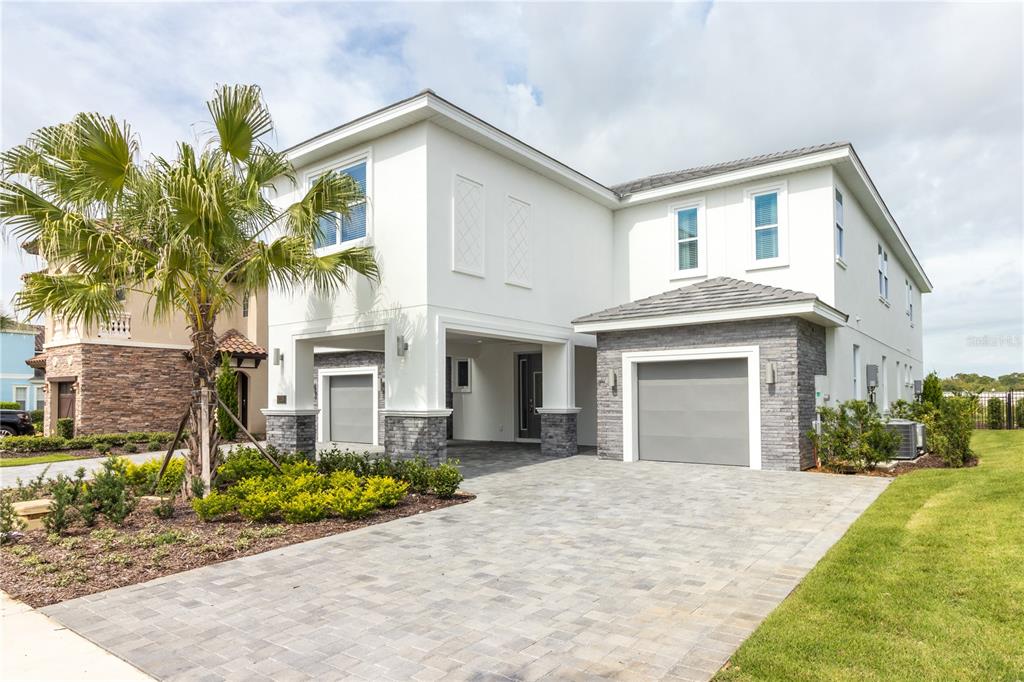 A two-story house with a white exterior, stone accents, a paved driveway, and a garage — 1136 CASTLE PINES COURT, REUNION, FL