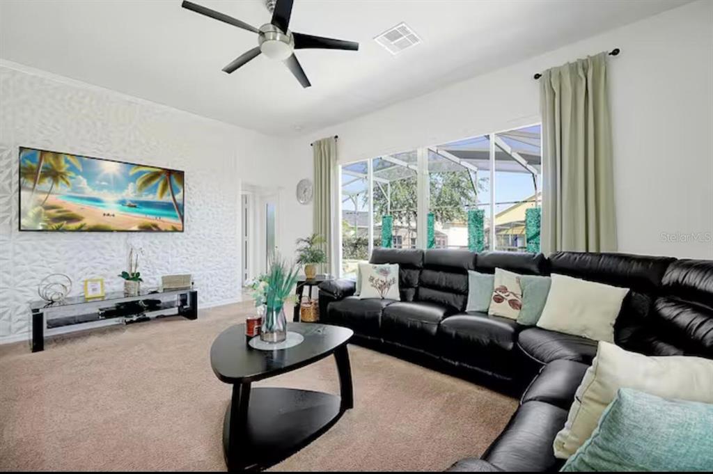 A living room features a black sectional sofa, a triangular coffee table, and a textured wall — 559 CADIZ LOOP, DAVENPORT, FL