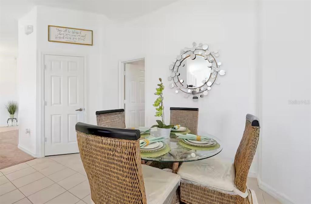 A dining area features a glass-topped table with four wicker chairs and a decorative wall mirror — 559 CADIZ LOOP, DAVENPORT, FL