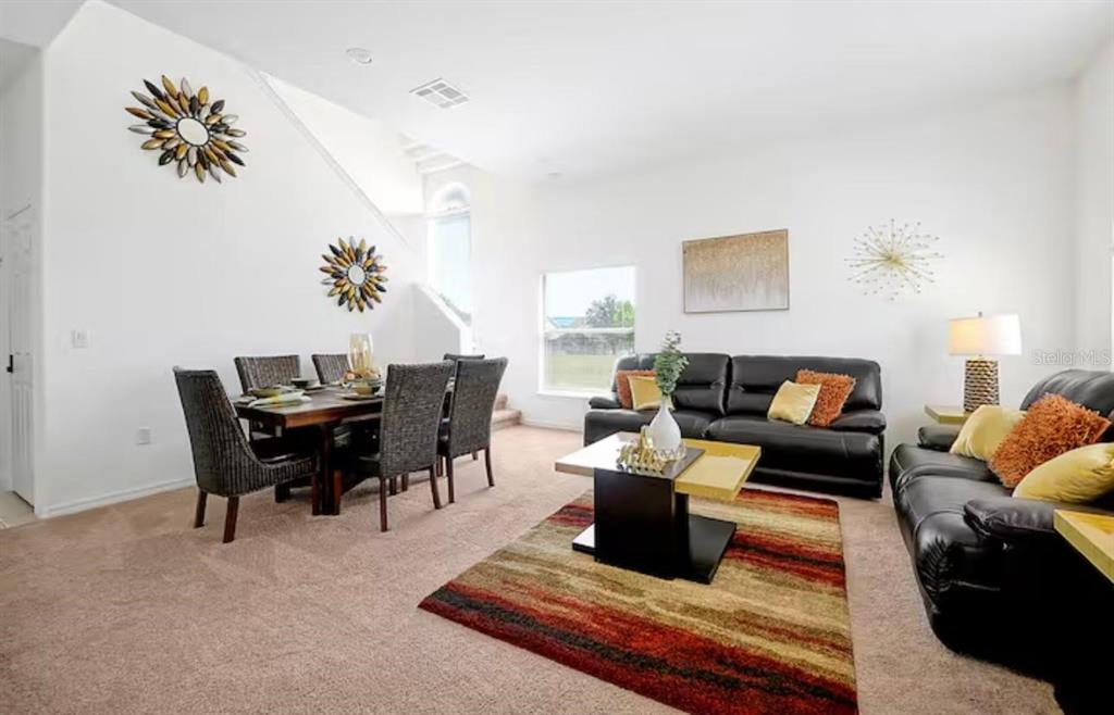 A living and dining area with black leather furniture, a striped rug, and wall decor — 559 CADIZ LOOP, DAVENPORT, FL