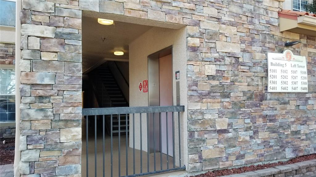 The exterior entrance of a stone-clad building features an elevator and a staircase — 8010 TUSCANY WAY UNIT 5308, DAVENPORT, FL