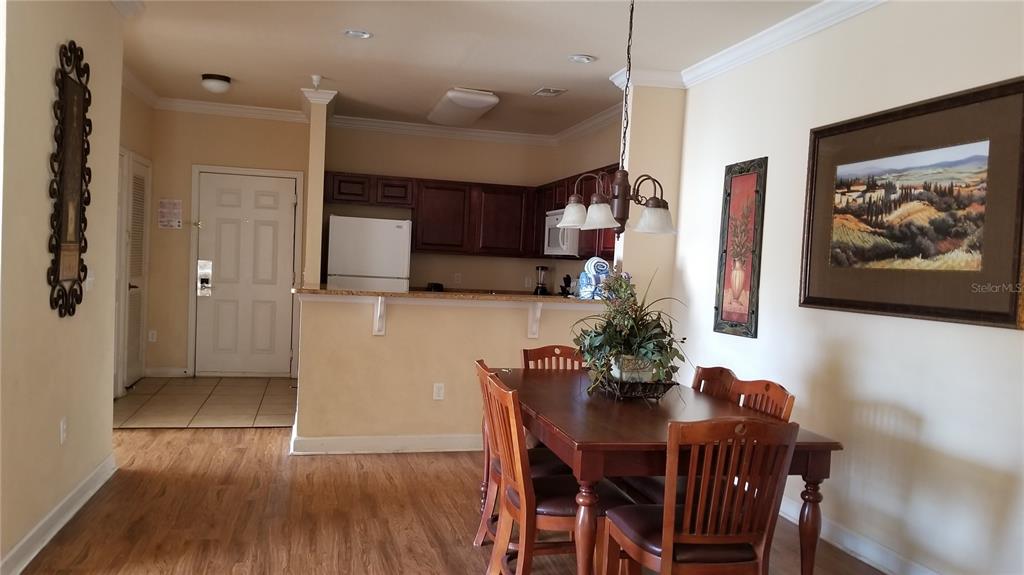 A dining area with a wooden table and chairs sits adjacent to an open kitchen — 8010 TUSCANY WAY UNIT 5308, DAVENPORT, FL
