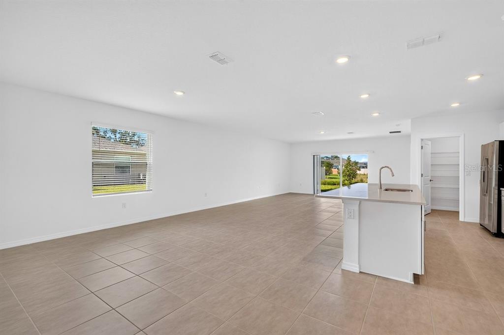 An open-concept living area features light tile flooring, white walls, and a kitchen island — 190 JONES FISH CAMP ROAD, EDGEWATER, FL