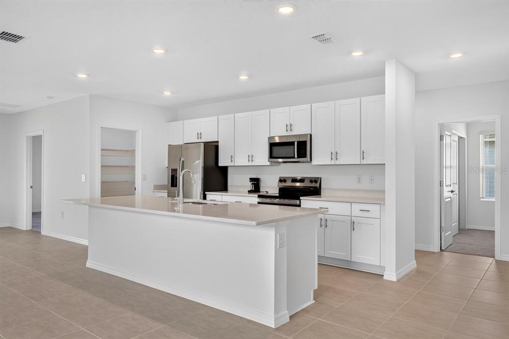 A modern kitchen features white cabinetry, stainless steel appliances, a large island, and tile flooring — 190 JONES FISH CAMP ROAD, EDGEWATER, FL