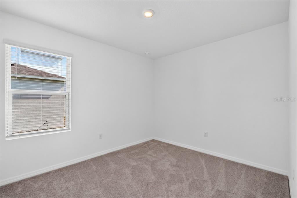 An empty bedroom features white walls, gray carpet, and a single window with blinds — 190 JONES FISH CAMP ROAD, EDGEWATER, FL