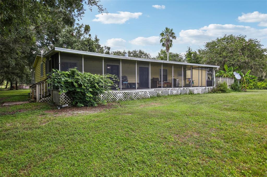 A yellow house features a large screened-in porch and lattice skirting on a grassy lot — 5321 BRUTON ROAD, PLANT CITY, FL