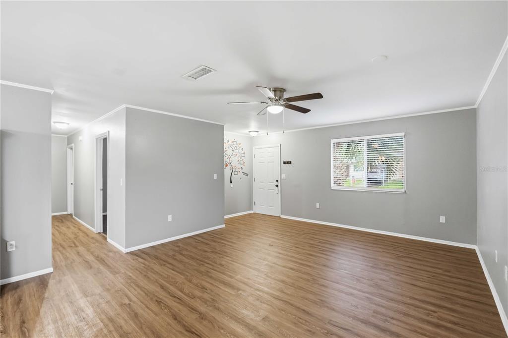 A spacious living room features gray walls, wood-look flooring, a ceiling fan, and a front door — 4057 VANA DRIVE, SARASOTA, FL