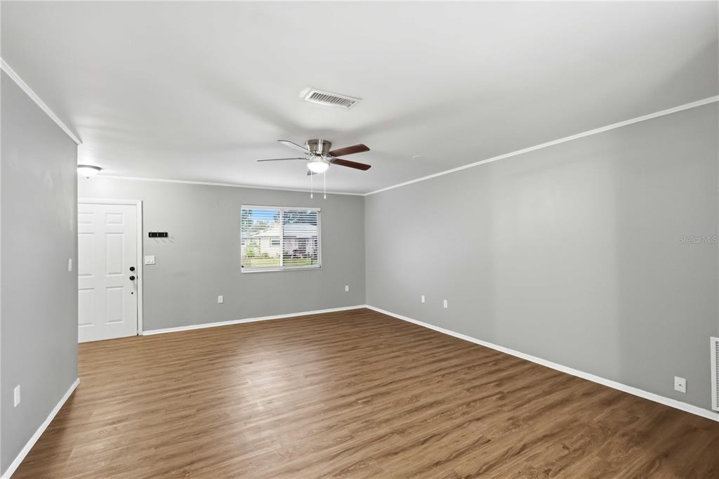 An empty living room features light gray walls, wood-look flooring, and a ceiling fan — 4057 VANA DRIVE, SARASOTA, FL