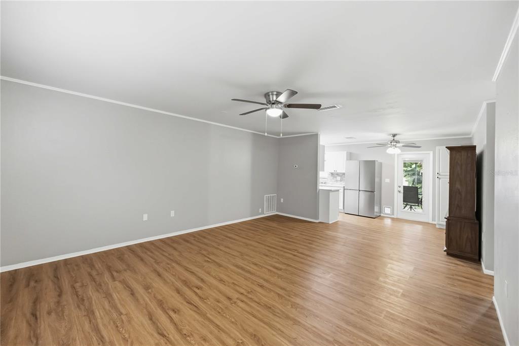 A spacious living room with light gray walls, wood-look flooring, and two ceiling fans — 4057 VANA DRIVE, SARASOTA, FL