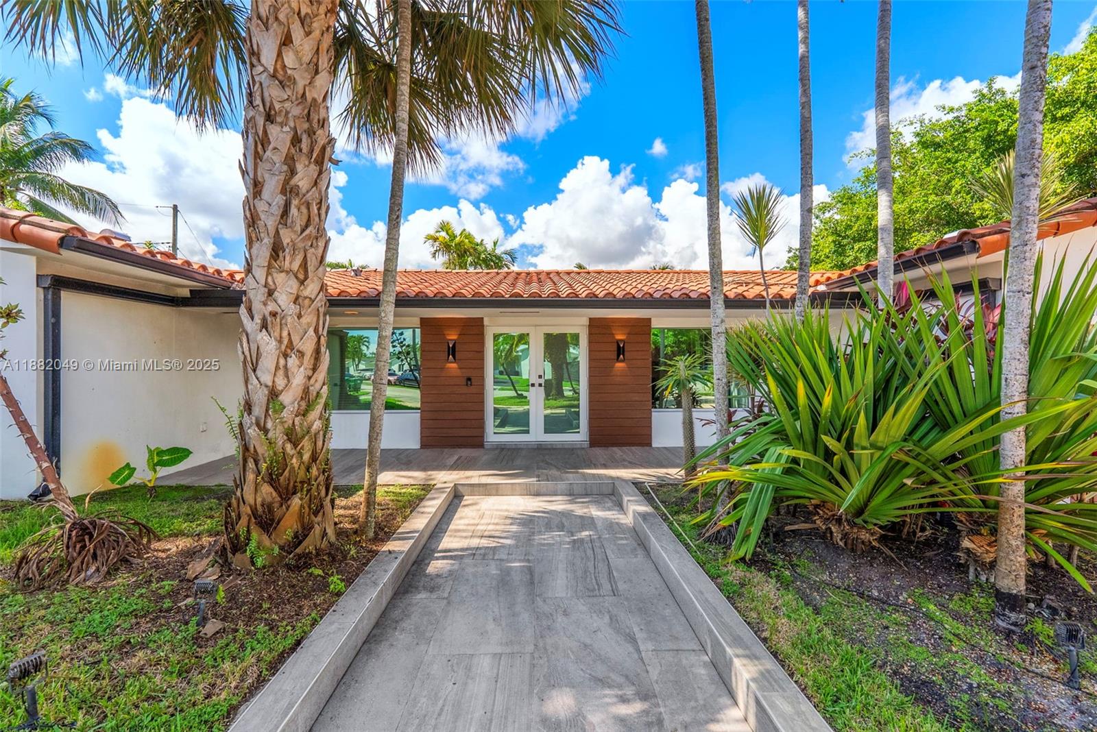 A paved walkway leads to the glass-paned double front doors of a house with palm trees — 21000 NE 18th Ct, Miami FL 33179, MIAMI, FL