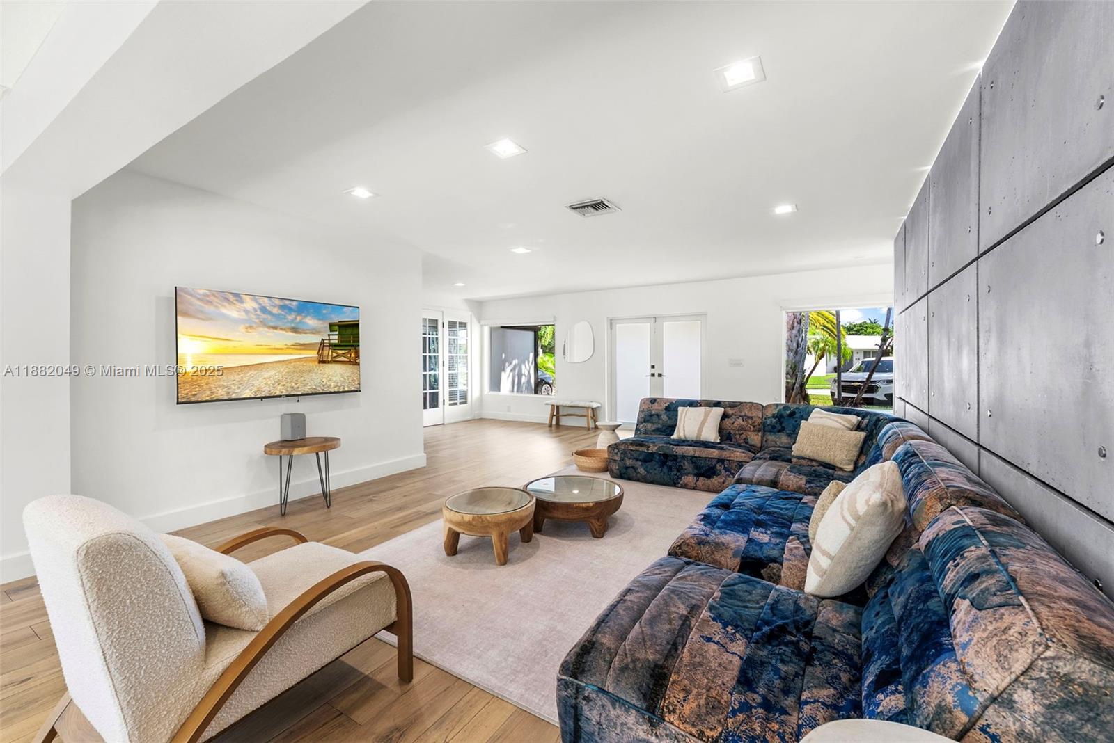 A living room features a large blue patterned sectional, a cream armchair, and a wall-mounted television — 21000 NE 18th Ct, Miami FL 33179, MIAMI, FL