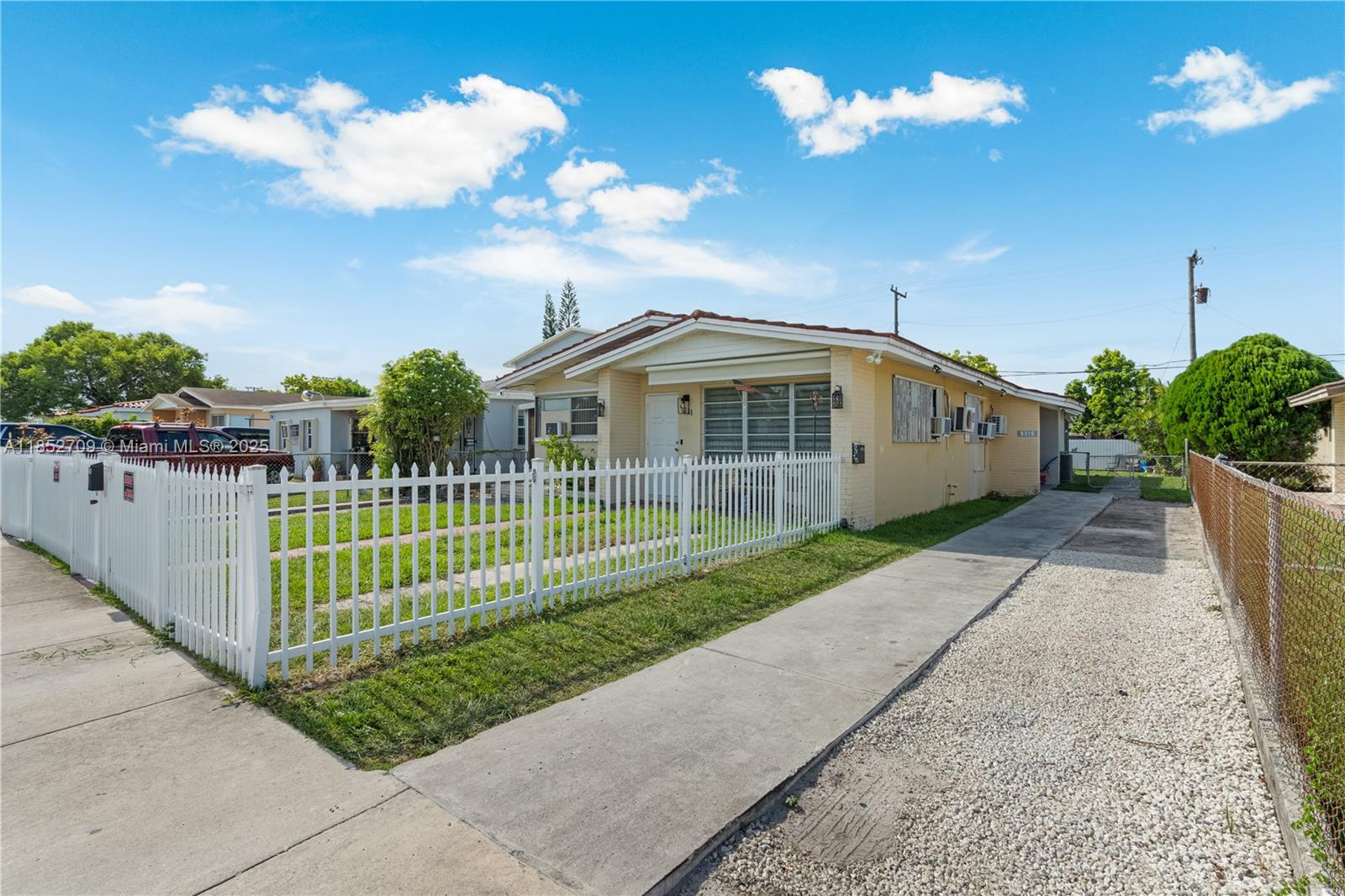 A single-story yellow house features a white picket fence and a concrete driveway — 9311 SW 37th St, Miami FL 33165, MIAMI, FL