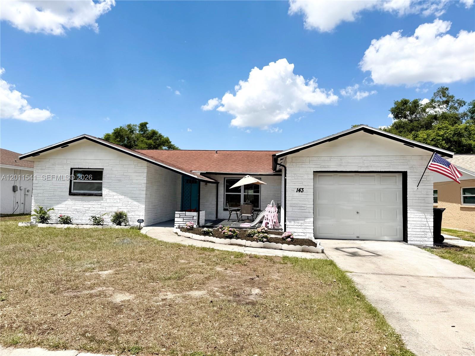 A white brick, single-story house features a front-facing garage, a small patio, and a lawn — 143 VALLEY CIR, Tampa FL 33510, TAMPA, FL