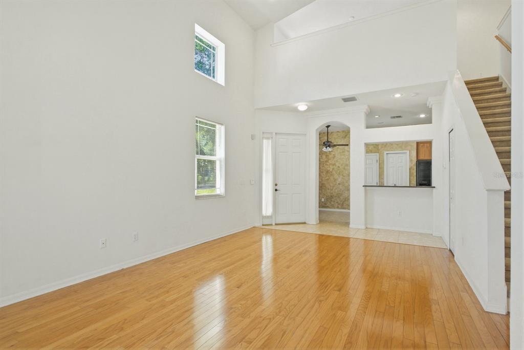 A living room with high ceilings, hardwood floors, and a staircase leading to an upper level — 1405 RIDGE TERRACE, TARPON SPRINGS, FL