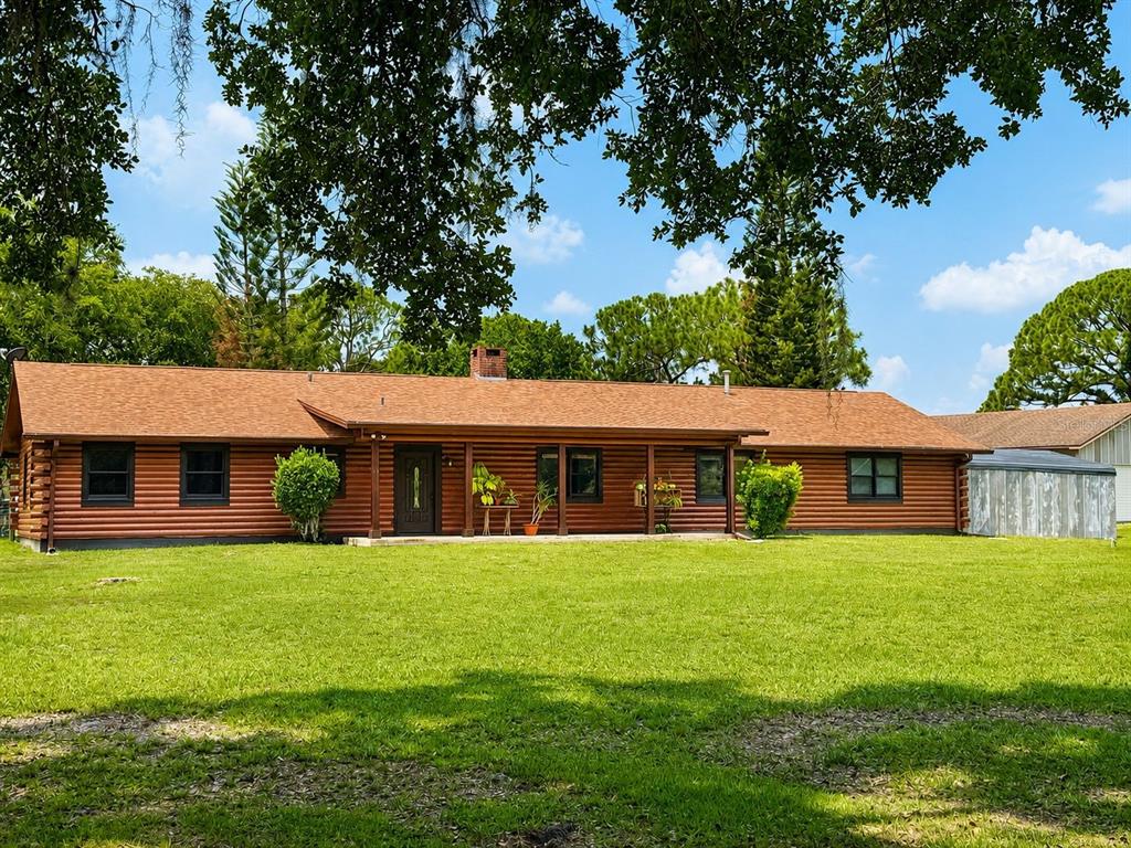 A single-story log cabin home with a brown shingled roof and a large front lawn — 545 CHASE HAMMOCK ROAD, MERRITT ISLAND, FL