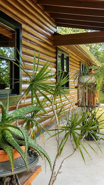 A log cabin exterior features a porch with potted plants and a window — 545 CHASE HAMMOCK ROAD, MERRITT ISLAND, FL