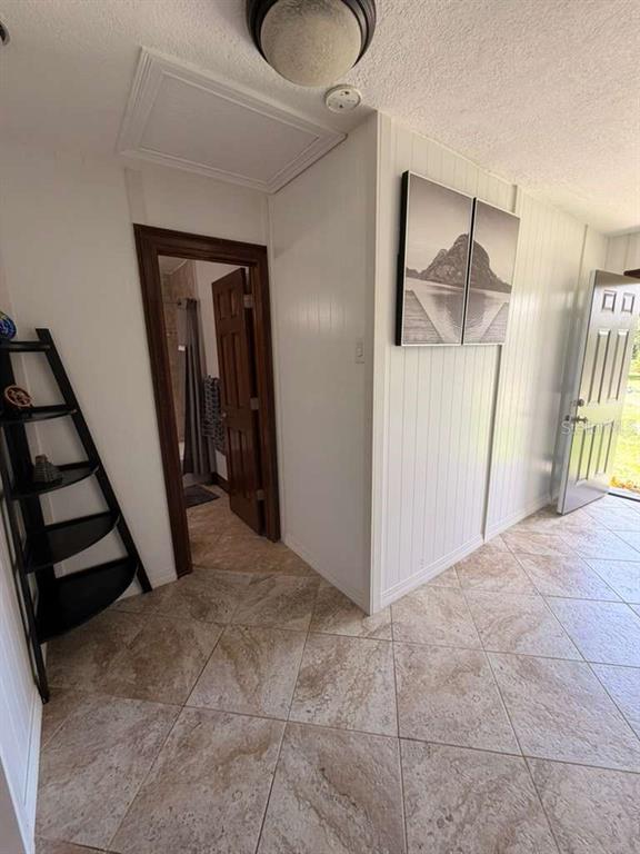 A tiled entryway features a black corner shelf, a doorway to a bathroom, and wall art — 1150 MAGNOLIA DRIVE, ALTAMONTE SPRINGS, FL