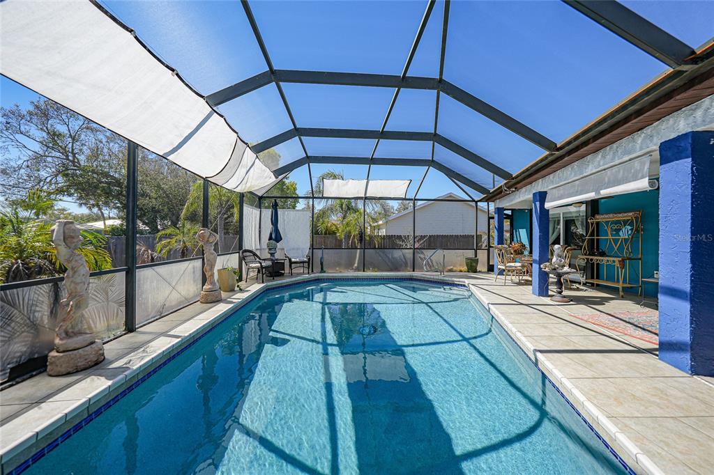 A screened-in swimming pool with a tiled deck and a blue accent wall — 19823 MIDWAY BOULEVARD, PORT CHARLOTTE, FL