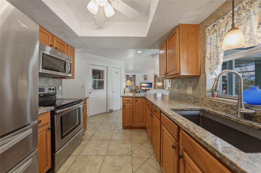 A kitchen with wood cabinets, granite countertops, stainless steel appliances, and tile flooring — 19823 MIDWAY BOULEVARD, PORT CHARLOTTE, FL