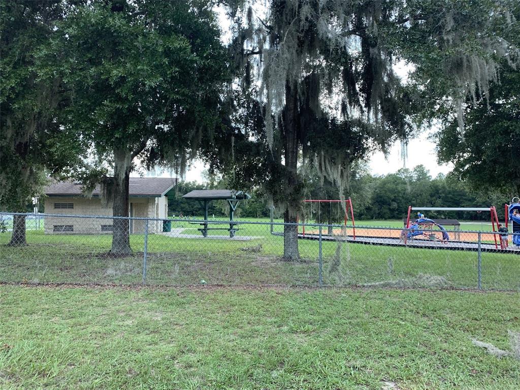 A fenced park area features a small building, a picnic shelter, and a playground — 8178 N FEATHER AVENUE, DUNNELLON, FL