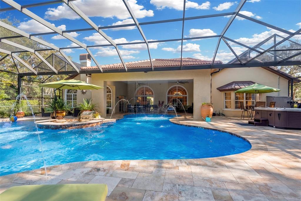 A swimming pool with fountains and a hot tub under a screened-in patio enclosure — 8 RUE RENOIR, PALM COAST, FL