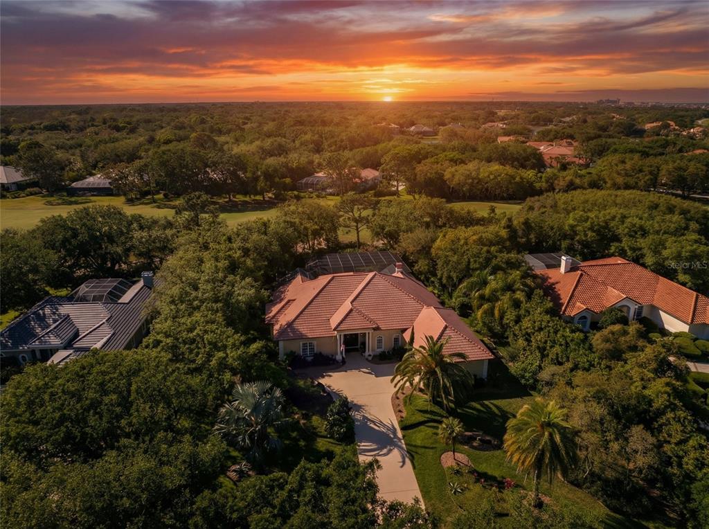 An aerial view of a house with a tile roof surrounded by trees at sunset — 8 RUE RENOIR, PALM COAST, FL