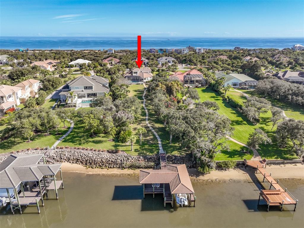 An aerial view shows a waterfront house with a private dock and a long walkway — 104 ISLAND ESTATES PARKWAY, PALM COAST, FL