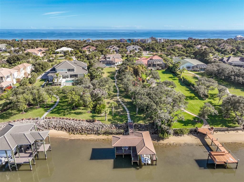 An aerial view shows waterfront houses with private docks and a sandy shoreline — 104 ISLAND ESTATES PARKWAY, PALM COAST, FL