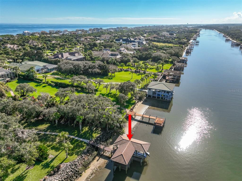 An aerial view shows a boat dock with a tiled roof extending into a waterway — 104 ISLAND ESTATES PARKWAY, PALM COAST, FL