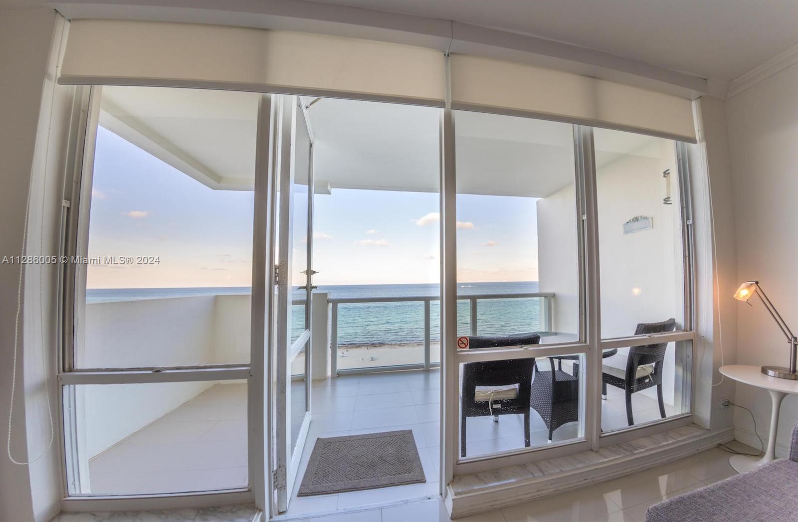 A room with large glass doors opens onto a balcony overlooking the ocean and beach — 5601 Collins Ave # 1206, Miami Beach FL 33140, MIAMI BEACH, FL