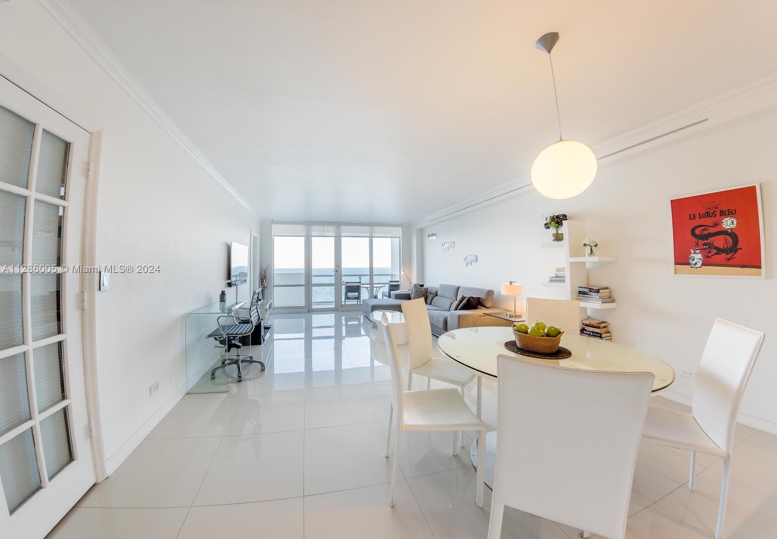 A bright living and dining area features white tile floors, a glass table, and ocean views — 5601 Collins Ave # 1206, Miami Beach FL 33140, MIAMI BEACH, FL