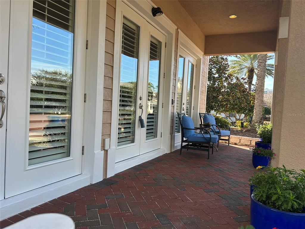 A covered brick patio features two blue chairs and glass-paned double doors — 6101 YEATS MANOR DRIVE, TAMPA, FL