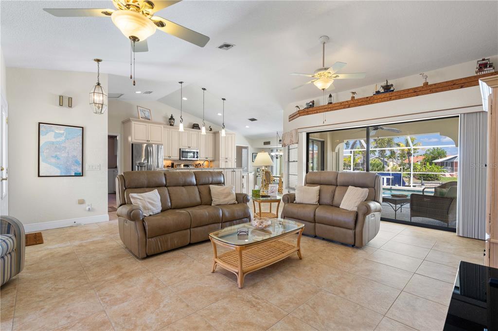 A living room with tile floors, two brown sofas, and a view of a pool — 1374 WILLET COURT, PUNTA GORDA, FL