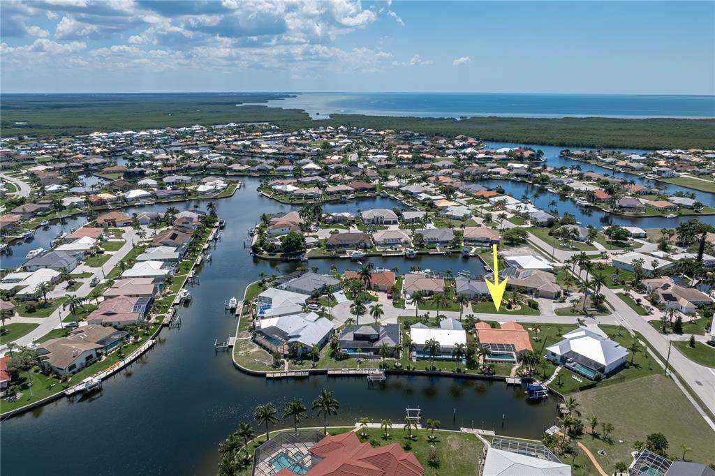 An aerial view shows a waterfront residential neighborhood with a yellow arrow pointing to a house — 1374 WILLET COURT, PUNTA GORDA, FL