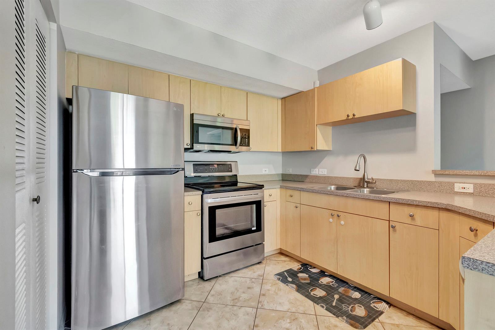 A kitchen features light wood cabinets, stainless steel appliances, and a tiled floor — 116 Villa Circle # 116, Boynton Beach FL 33435, BOYNTON BEACH, FL