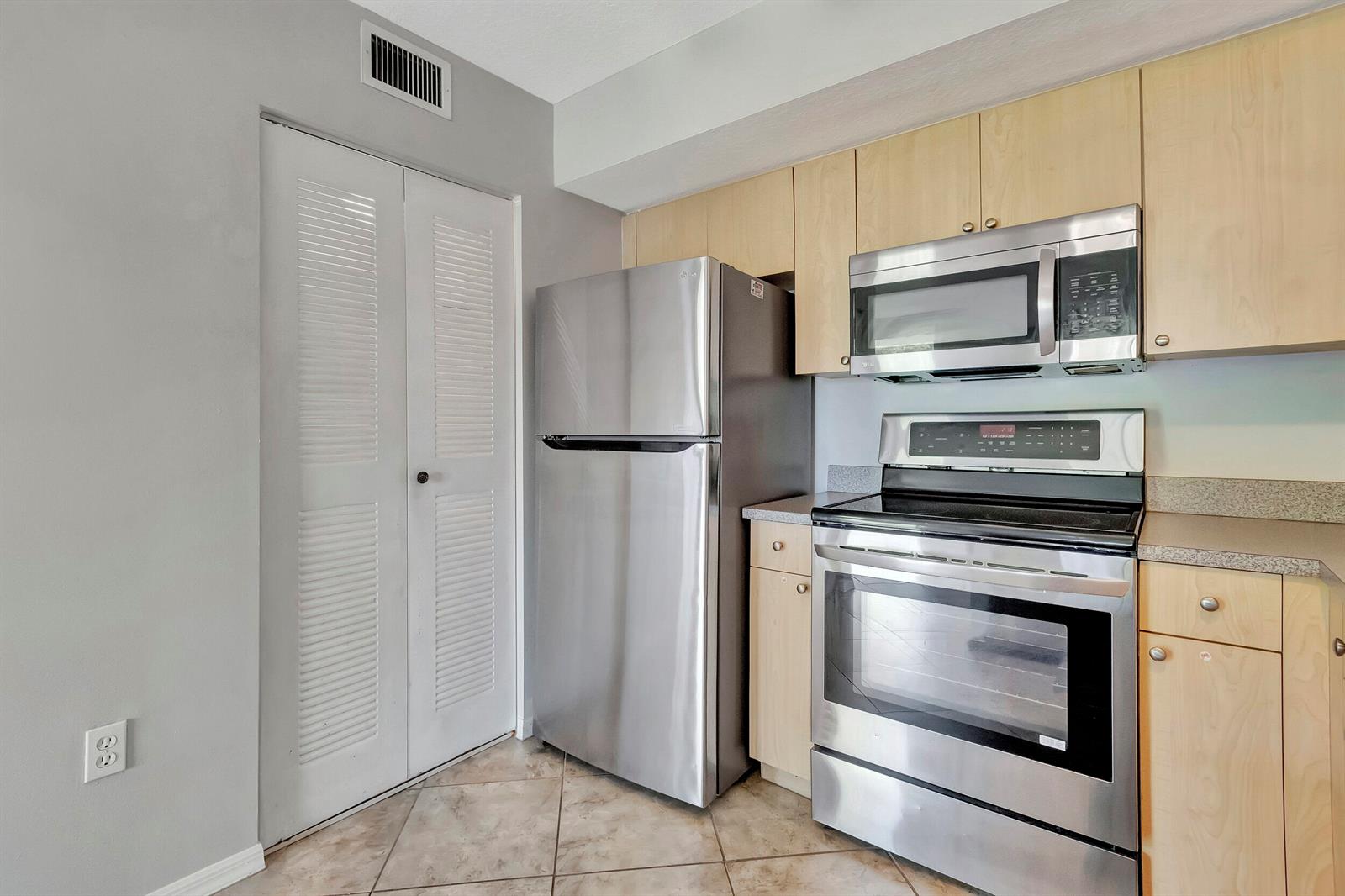 A kitchen features stainless steel appliances, light wood cabinets, and tiled flooring — 116 Villa Circle # 116, Boynton Beach FL 33435, BOYNTON BEACH, FL