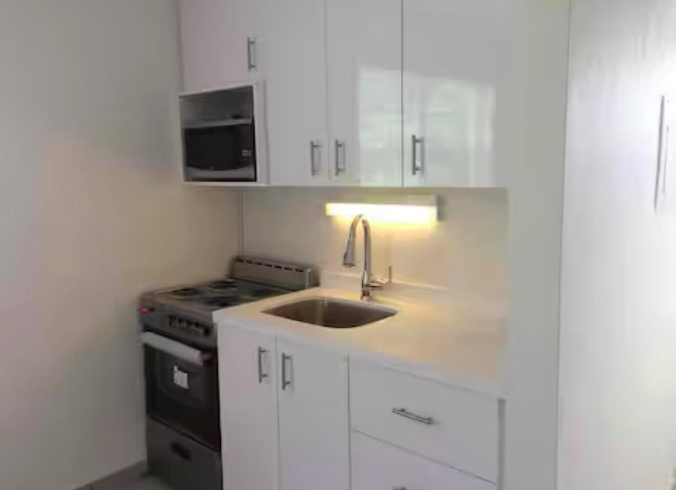 A compact kitchen features white cabinets, a stainless steel stove, and a built-in microwave — 41 NE 1st Avenue # 4, Dania Beach FL 33004, DANIA BEACH, FL