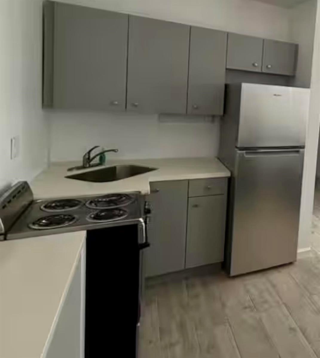 A small kitchen features gray cabinets, stainless steel appliances, and light-colored countertops — 41 NE 1st Avenue # 4, Dania Beach FL 33004, DANIA BEACH, FL