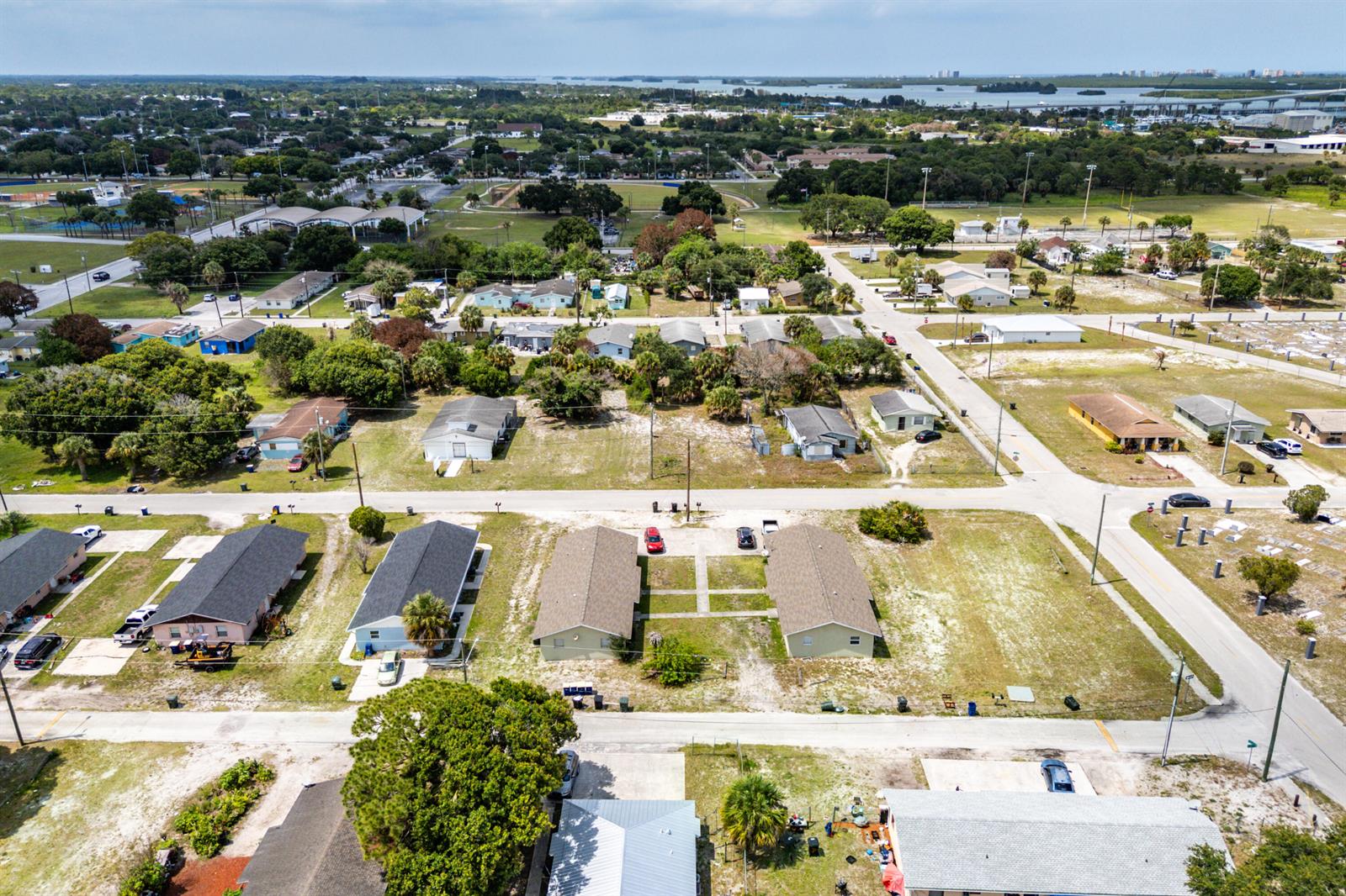 An aerial view shows a residential neighborhood with single-story houses, paved streets, and grassy lots — 1205 Ave K, Fort Pierce FL 34950, FORT PIERCE, FL