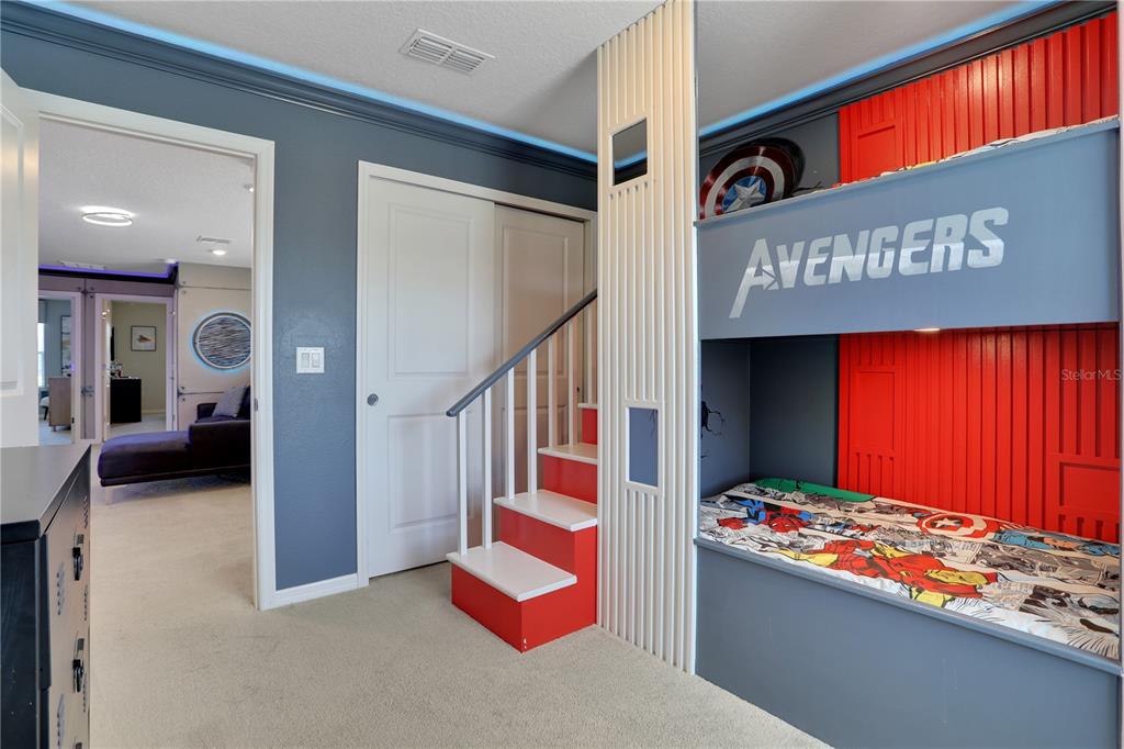 A bedroom features a custom Avengers-themed bunk bed with built-in stairs and blue wall paint — 900 PARADISE DRIVE, DAVENPORT, FL