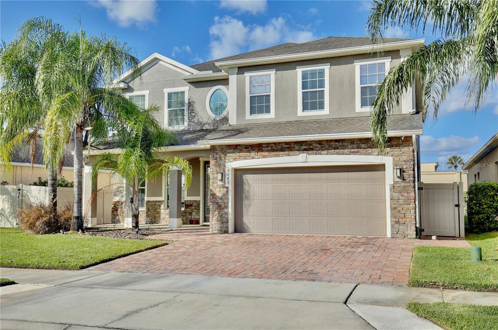 A two-story suburban house with a stone facade, a two-car garage, and palm trees — 6049 FENDER COURT, ORLANDO, FL