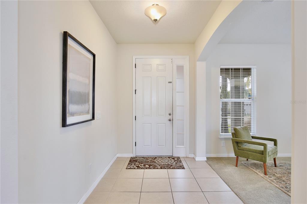 A tiled entryway features a white front door, a framed wall print, and a green chair — 6049 FENDER COURT, ORLANDO, FL