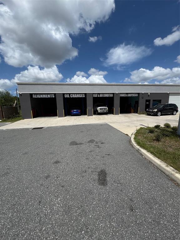 A commercial auto repair shop exterior features four service bays with labeled signage — 4825 OLD WINTER GARDEN ROAD, ORLANDO, FL