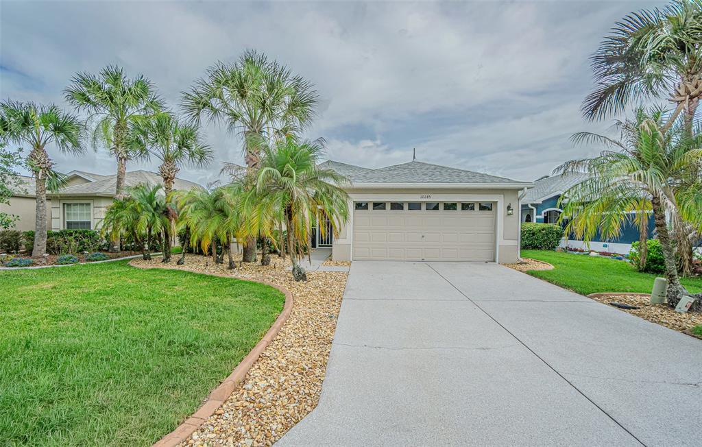 A single-story house with a two-car garage, palm trees, and a landscaped front yard — 10245 BUNCOMBE WAY, SAN ANTONIO, FL