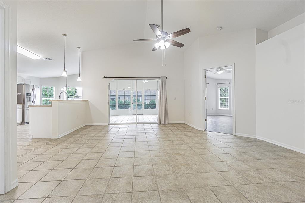 A living room with tile floors, a vaulted ceiling, and an open kitchen area — 10245 BUNCOMBE WAY, SAN ANTONIO, FL