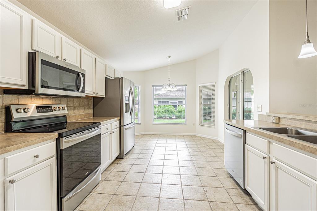 A kitchen with white cabinets, stainless steel appliances, and a dining area with a table — 10245 BUNCOMBE WAY, SAN ANTONIO, FL