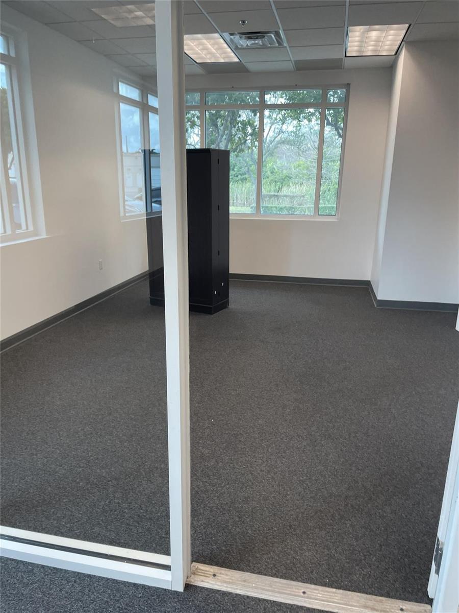An empty office space with gray carpet, white walls, and a large black storage cabinet — FORT LAUDERDALE, FL