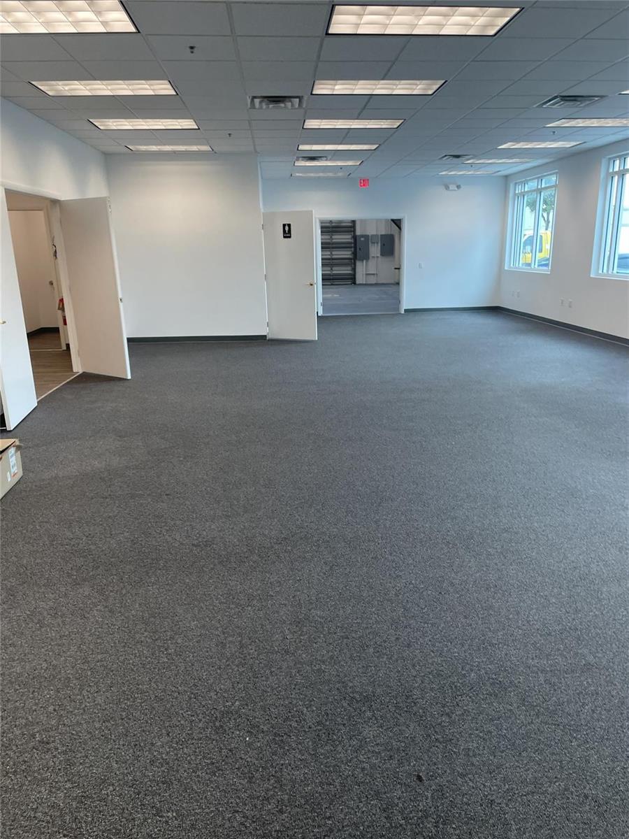 An empty office space features gray carpeting, white walls, a drop ceiling, and multiple doorways — FORT LAUDERDALE, FL
