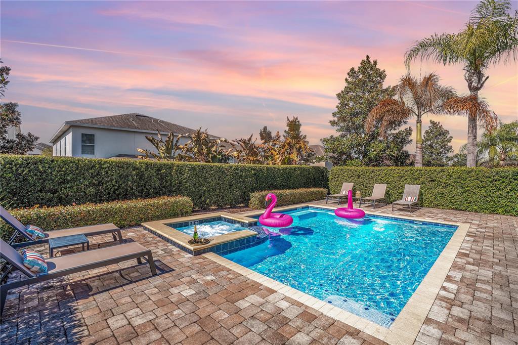 A backyard swimming pool and hot tub with lounge chairs and pink flamingo pool floats — 631 LASSO DRIVE, KISSIMMEE, FL